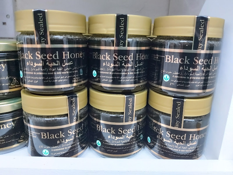 Jars of black seed honey stacked on a shop shelf